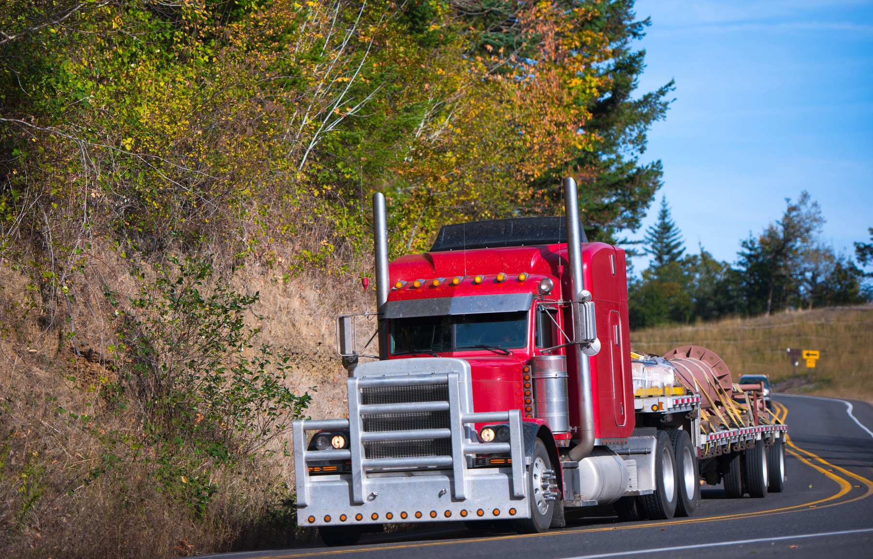 Red powerful big rig semi truck and step deck trailer